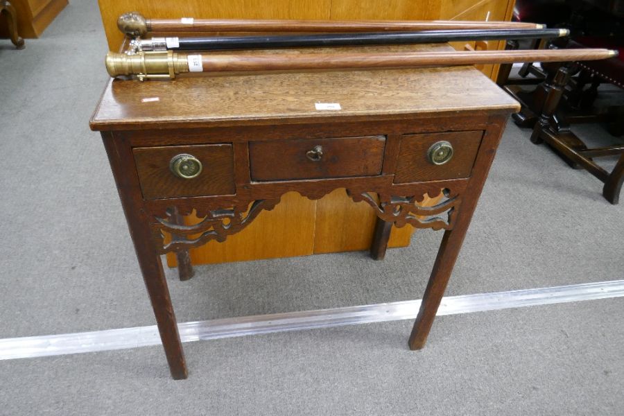 An antique oak low boy having three drawers on square chamfered legs