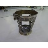 A heavily decorated white metal beaker holder, pierced decoration with two rams heads, dragons desig
