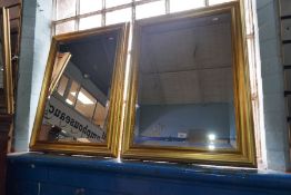 A pair of bevelled glass wall mirrors with gilt frames