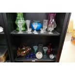 Two shelves of antique and later coloured glassware including five eye baths