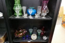 Two shelves of antique and later coloured glassware including five eye baths