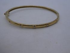 9ct yellow gold bangle set with 5 diamonds, marked 375, approx. 6cm diameter, clasp broken. 11.9g ap