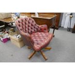 A repro red leather revolving desk chair having buttoned upholstery