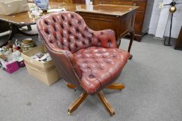 A repro red leather revolving desk chair having buttoned upholstery