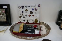 A plated decorative tray containing assorted items including penknives, lighters, coins of various d