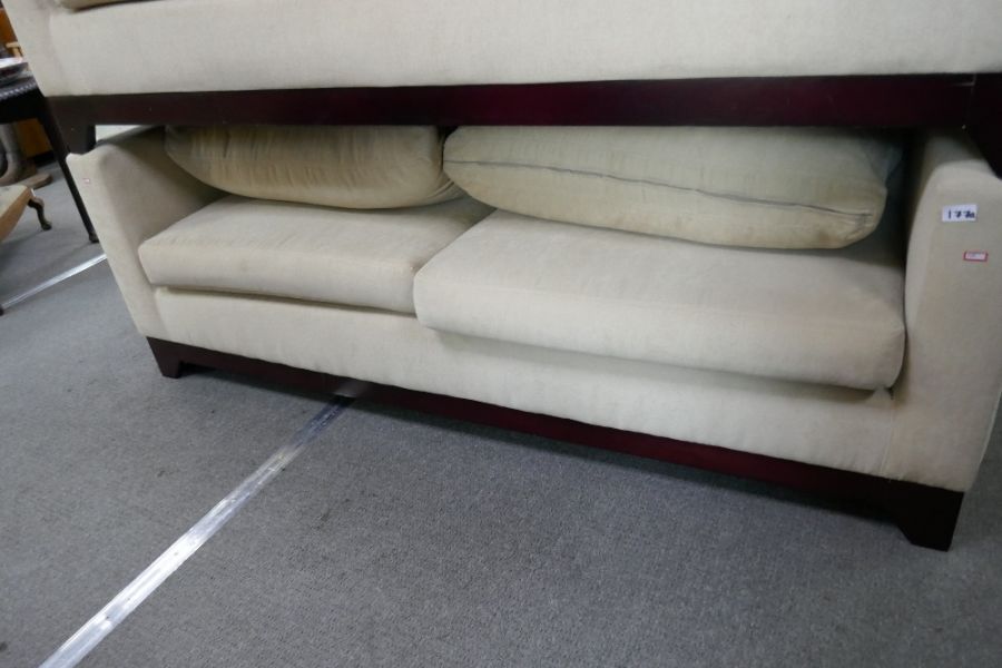 A modern 2 seat sofa upholstered in cream fabric