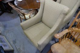 Two Victorian lounge armchairs upholstered in green and gold fabric on tapered supports