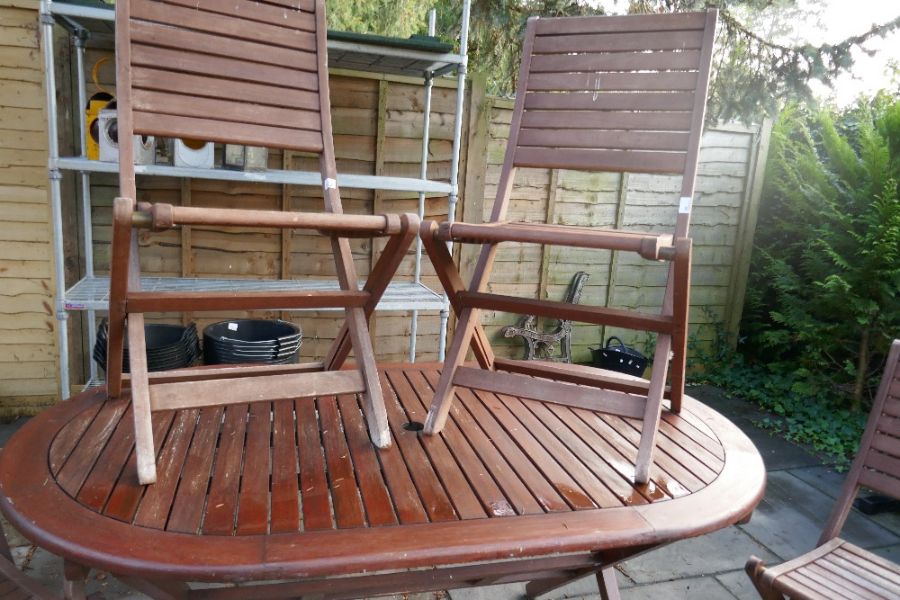Oval teak garden table, four chairs and an armchair