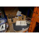 A wicker basket containing glasses, advertising items and silver cutlery etc