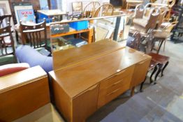 A mid century teak mirror back sideboard, with three central drawers flanked by cupboards, on tapere