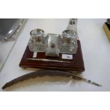 A silver and wooden desk stand with two silver topped glass square inkwells, a silver pen and wooden