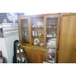 A modern oak display cabinet having glass doors with drawers and cupboards below