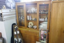 A modern oak display cabinet having glass doors with drawers and cupboards below