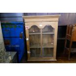 A smalled stripped pine hanging bookcase having glazed door