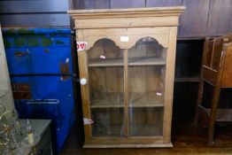 A smalled stripped pine hanging bookcase having glazed door