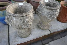 A pair of small reconstituted garden urns decorated lion masks