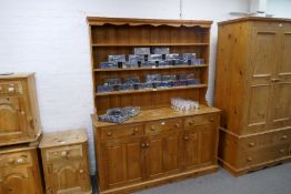 Large waxed pine dresser with open rack above three drawers and cupboards
