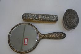 Silver backed dressing tale items to include a repoussed design mirror, a matching brush, and a silv