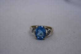 Contemporary 9K yellow gold dress ring set large blue topaz and the shoulders with diamond chips, ma
