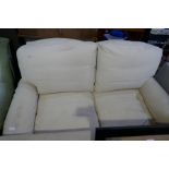 A modern cream two seat settee on turned front legs