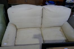 A modern cream two seat settee on turned front legs