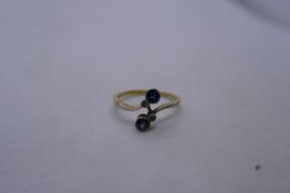 18ct two tone crossover design ring inset with two pale blue sapphires and two small diamonds, marke