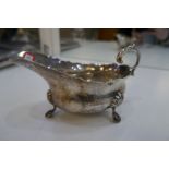 A Harrods London silver sauce boat with scalloped border on three feet. Hallmarked London Harrods Lt