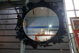 A circular wall mirror frame with decorated figures