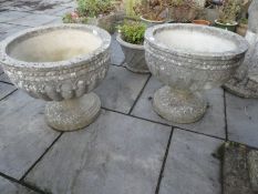 A pair of reconstituted urns having reeded decoration