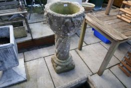 An antique stone pedestal font decorated figures on twisted pillar