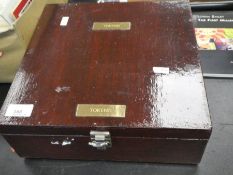 A wooden case containing coins, tokens and similar