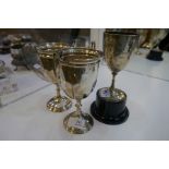 A pair of silver trophy cups with half reeded design and two handles, standing on a raised pedestal