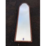 A Queen Anne style walnut framed mirror with arched cushion moulded frame. (49.5in x 13.5in)