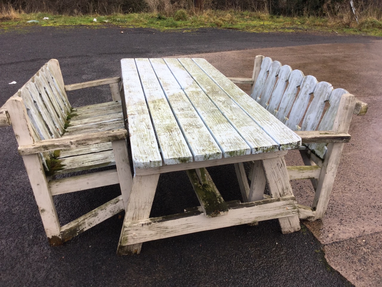 A six foot garden table and two matching benches, the table with six plank top and seats with shaped