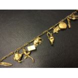 A gilt metal linked bracelet with several 9ct gold charms - a teapot, a sprung jack-in-the-box, a