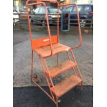 A work platform by Hi-Way, the tubular frame with handrails having two treads up to rectangular top,