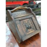 A Victorian carved oak coal skuttle, with flowerhead chisel carving to handle and top, having angled
