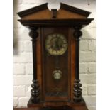 A late Victorian Vienna wallclock with angled broken pediment above an arched door flanked by fluted