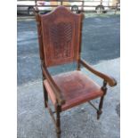 An Egyptian armchair, the arched leather back panel embossed with stylised decoration having greek