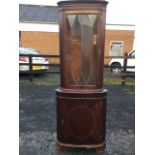 A bowfronted mahogany corner cabinet with moulded dentil cornice above an astragel glazed door,
