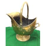 A Victorian brass helmet shaped coal skuttle with rolled rim and swing handle, the body with