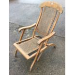 A late Victorian folding steamer armchair with rectangular cane back & seat, having arched back rail