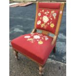 A late Victorian oak chair with floral crewelwork to studded upholstery, the back with chisel