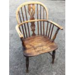 A nineteenth century elm windsor chair the spindled back and bow arms around a pierced shaped splat,