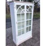 A reproduction painted glazed bookcase with limed moulded cornice above arched astragal fretwork