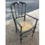 A Victorian ebonised childs armchair decorated with gilt leaf brushwork, the scalloped back on