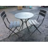 A circular metal garden table and chair set, the folding pair of chairs with slatted backs and