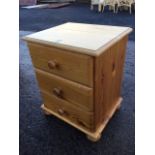 A reproduction pine dwarf chest with moulded top above three knobbed drawers, raised on bun feet. (