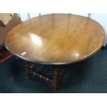 An Ercol elm coffee table, the oval top with drop-leaves on gates, supported on square chamfered