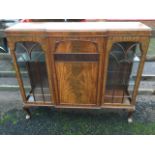 A breakfront mahogany side cabinet with moulded top above a central panelled door with applied